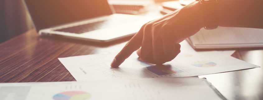 Businessman pointing finger analyzing statistics financial graph
